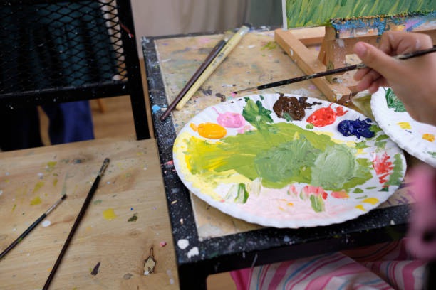 An artist colors palette, painting a colorful acrylic picture in the studio. stock photo