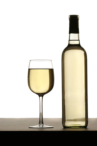 Glass of white wine with bottle on table, isolated stock photo