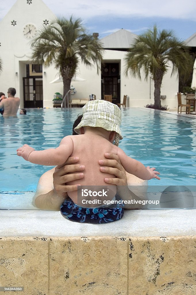 Pai segurando o bebê com chapéu na beira da piscina - Foto de stock de Atividades de Fins de Semana royalty-free