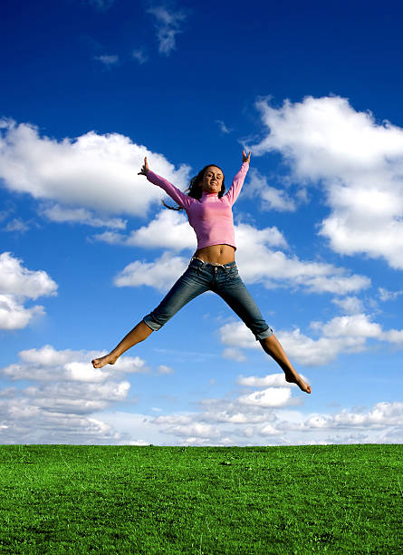 Happy young beautiful girl jumping in the green field. stock photo