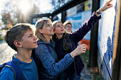 Family standing by street hiking map in a small town in Tatra Mountains and planning the hiking route