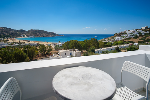 Amazing view from a balcony with a chair and a table overlooking the famous Mylopotas beach in Ios Greece