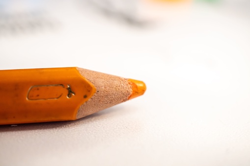 A close-up of an orange wooden pencil on the white background