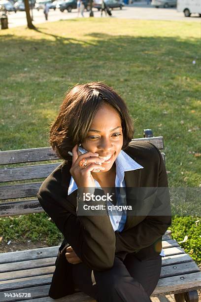 Uśmiechająca Się African American Kobieta Telefon Komórkowy Siedzi Ławka Parkowa Poza - zdjęcia stockowe i więcej obrazów 20-29 lat