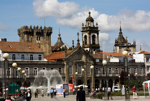 Braga, Portugal- May 5, 2011:República town square, Braga city, Portugal. Ancient facades and towers, ornamental fountain, group of incidental people walking, city life.