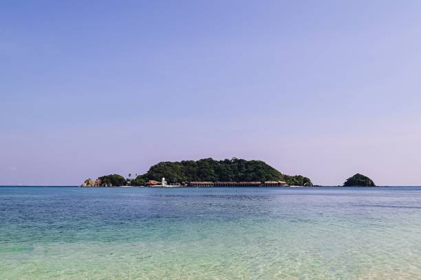 istock Island covered with trees and a building on the shore on a cloudless day 1443457578