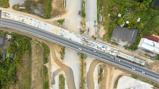 Aerial image of a road construction machine During the asphalting process, an asphalt paver, roller, and truck are seen on the road repair site. Top-down aerial picture of tram track repair.