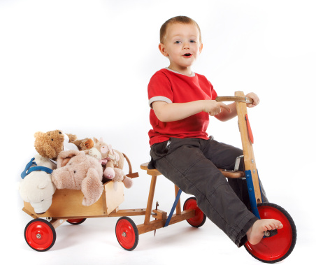 Little boy transporting his teddy bears and dolls in a cart