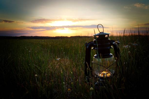 A camping lantern in the field at beautiful sunset