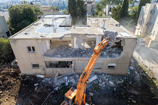 Dismantling of a house. Excavator demolishing barracks for a new construction project.