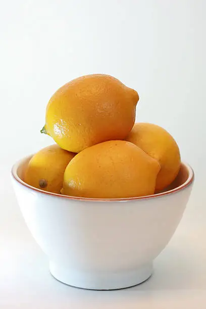 A white bowl filled with lemons.