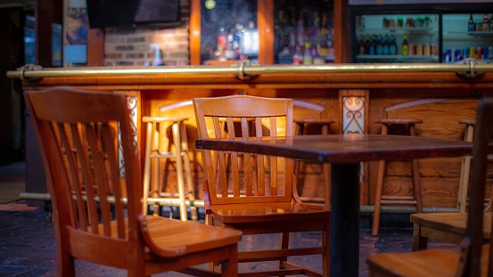 A closeup of wooden chairs and a table with a bar counter on the background