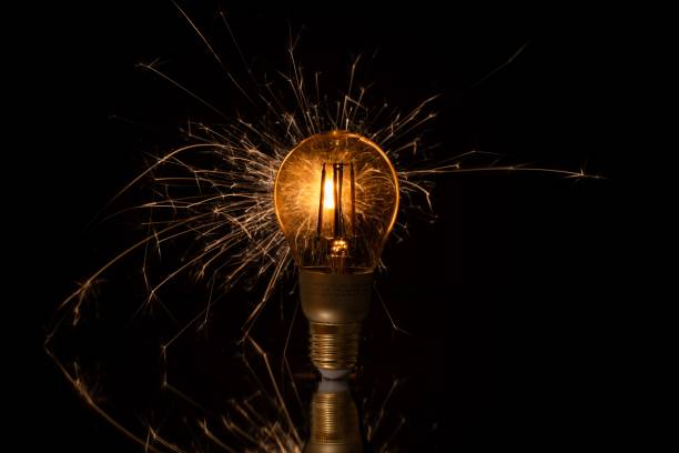 istock Long exposure of a lightbulb with sparks on a reflecting surface on a black background. 1443466524