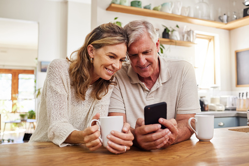 Senior couple on smartphone reading online social media post, search holiday house website or retirement planning inspiration with home wifi. Happy elderly pension people with cellphone chat app