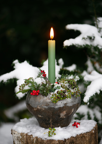 Christmas candles with traditional decorative stars , red baubles , pine cones and green branches on snow