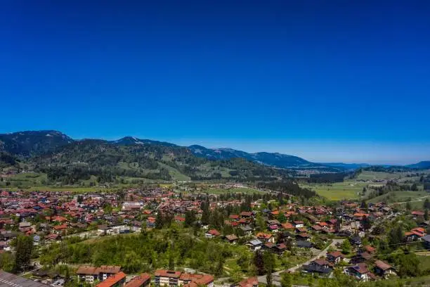 An aerial drone view of Kempten town surrounded by beautiful  Alpine mountains against a blue sky