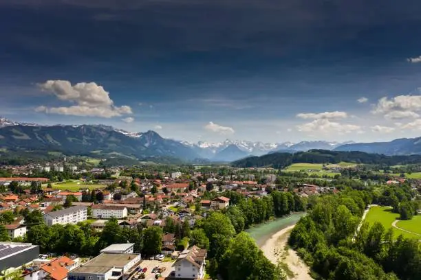 An aerial drone view of Kempten town surrounded by beautiful  Alpine mountains against a blue sky