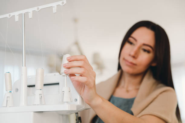 istock Young woman seamstress sets white threads in sewing machine, entrepreneurship concept. 1443470876