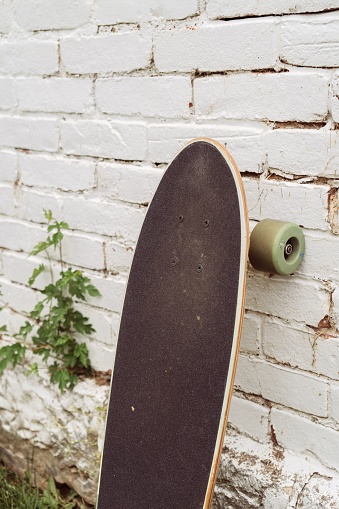 A vertical closeup shot of a skateboard leaning on brick wall