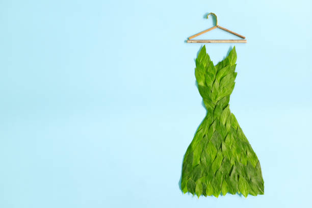 nachhaltiges und umweltfreundliches modekonzept. kleid aus frischen grünen blättern auf blauem hintergrund. - fashion industry textile man made material green stock-fotos und bilder