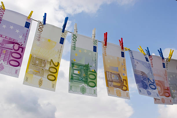 Money-laundering Euro banknotes on a clothesline against cloudy sky money laundering stock pictures, royalty-free photos & images