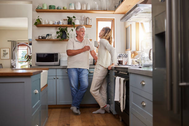 entspannen sie sich, kaffee und älteres paar in einer küche, verbinden und reden in ihrem haus zusammen. liebe, frau und reifer mann genießen ruhestand und beziehung drinnen, zwanglose gespräche am morgen - senior couple couple partnership discussion stock-fotos und bilder