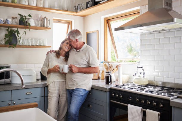 l’amour, la cuisine et le couple de personnes âgées se détendent avec une tasse de café, de thé ou de boisson chaude tout en créant des liens et en se connectant à la maison. famille, paix et personnes âgées homme et femme profitent de temps de - cuisine blanche photos et images de collection