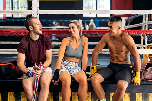 Young men and caucasian woman getting ready for boxing in the gym. Concept of kickboxing.