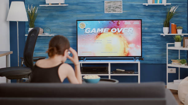 istock Young woman holding wireless controller playing action space shooter disappointed because losing online game 1443482775