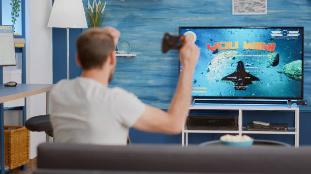 istock Gamer holding controller celebrating victory in online first person shooter game 1443482946
