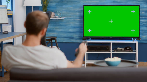 istock Static tripod shot of man switching channels while looking at green screen on tv 1443483390