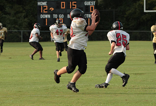 istock Young boy catching football running towards endzone 144348550
