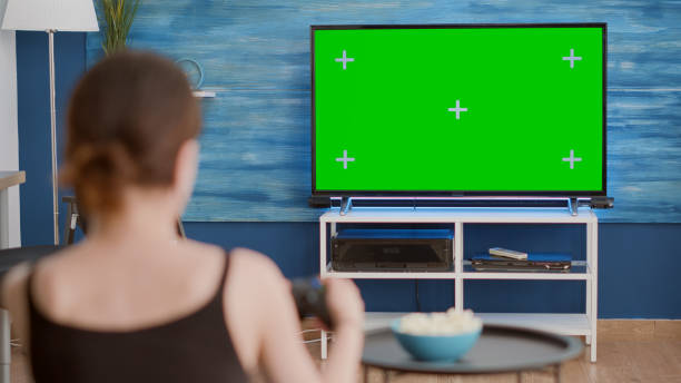 istock Over shoulder view of young woman playing console video games with wireless controller on green screen tv 1443486708