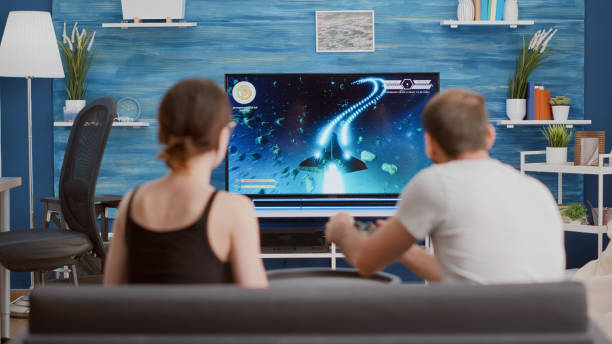 istock Gamer playing console video game first person shooter on tv while girlfriend is eating popcorn and giving him advice 1443486932