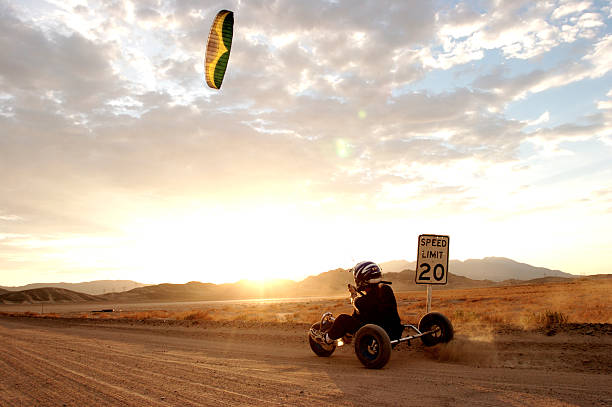 Deset Kite Buggying A man kite buggies on a deserted desert road at sunset airfoil photos stock pictures, royalty-free photos & images