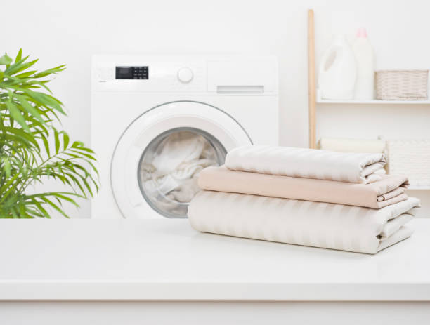 pila de sábanas limpias sobre el fondo borroso de la lavandería - washing fotografías e imágenes de stock