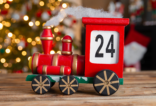 Wooden train Christmas advent calendar. Countdown to Christmas festive decoration. Counting down the days until Christmas wood number blocks. With tree lights bokeh in background.