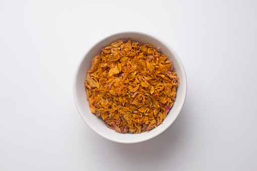 Fried garlic Bawang Goreng in a white bowl on a white background top view