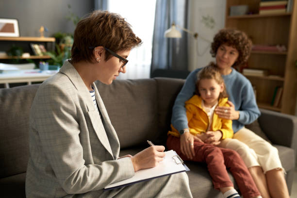 Social worker talking to family at home Social worker making notes in document while talking to difficult child and his mom at home community outreach stock pictures, royalty-free photos & images