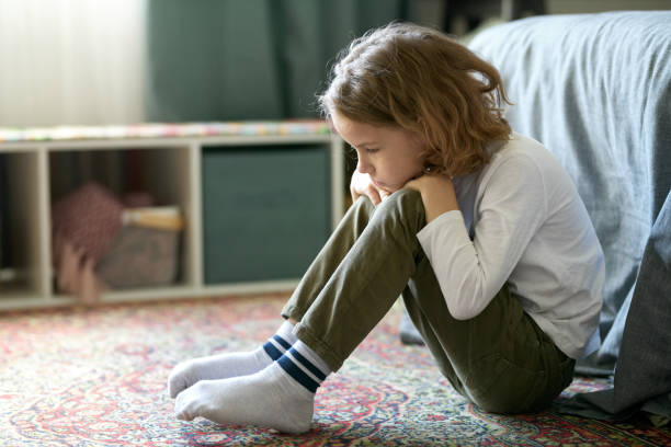 little boy feeling lonely sitting in bedroom - little boys child sadness depression imagens e fotografias de stock