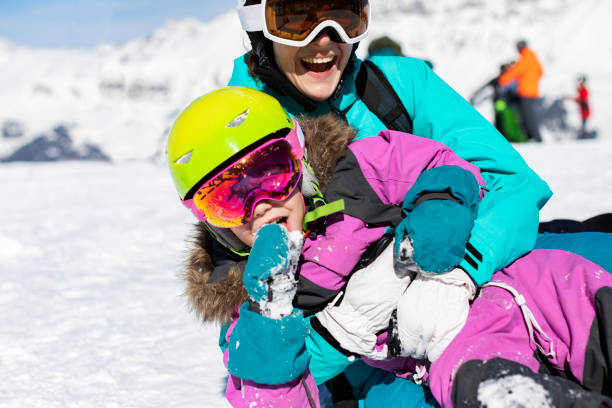 Mother and daughter skiing in mountains together and having fun stock photo
