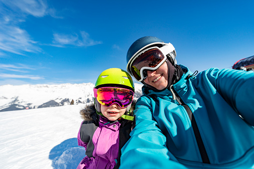 Mother and daughter skiing in mountains together and having fun