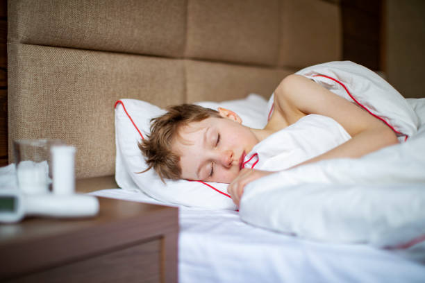 School age boy laying in bed with a flu