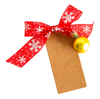 Kraft paper empty tag with red ribbon and bauble, Christmas ornaments on white or transparent background. Overhead view.