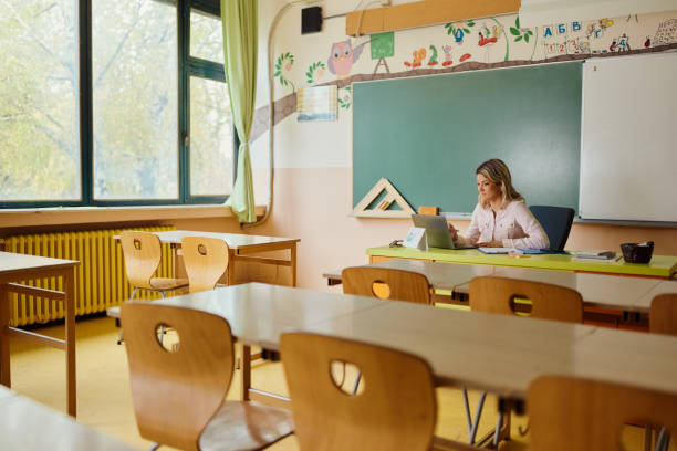 istock Smiling female teacher using laptop in the classroom. 1443497964