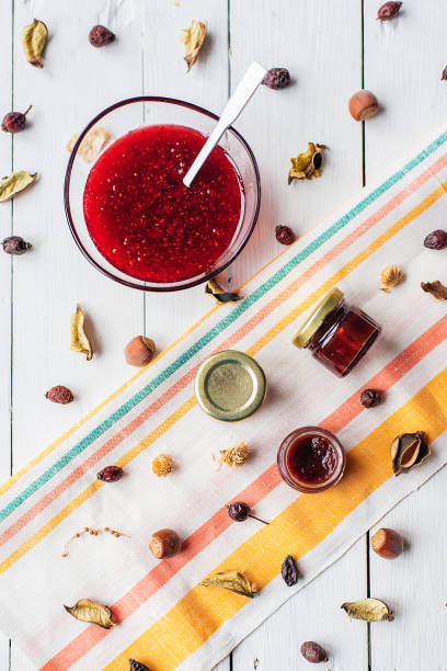 raspberry jam flat lay view. a jar of red marmalade with a spoon on a light-colored cloth. rustic decor made from dry leaves and nuts. healthly food
