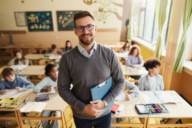 istock Happy elementary teacher in front of his students in the classroom. 1443499223