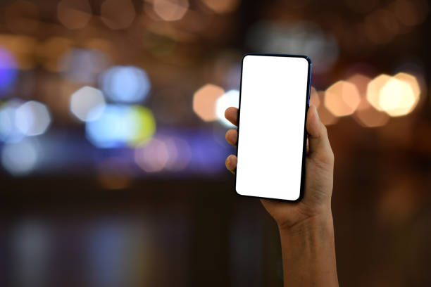 Hand holding smartphone with blank screen on bokeh light background stock photo