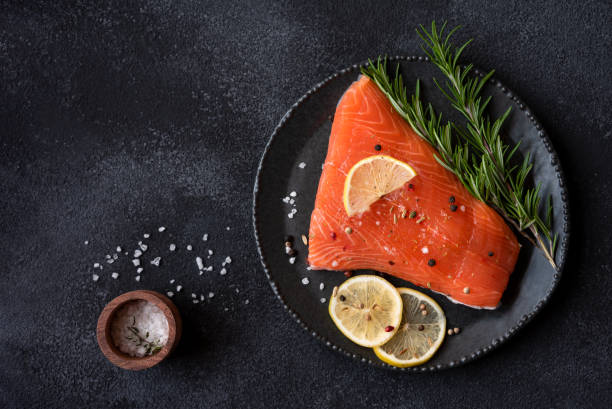 istock Uncooked raw salmon fish with herbs on dark background 1443499339