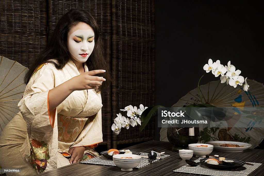 Beautiful young geisha girl in kimono drinking saki Adult Stock Photo